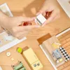 Hands assembling a miniature kitchen set on a wooden table. Podgląd zdjęcia produktu