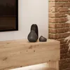 A close-up of a wooden TV cabinet with decorative vases on top, next to a brick wall. Produktbild-Vorschau