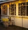 Decorative LED trees and icicle lights are displayed outside a house, illuminating the facade and windows. Produktbild-Vorschau