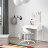 A child's desk setup in a room with a backpack, chair, and storage. Produktbild-Vorschau