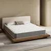 A mattress on a wooden bed frame in a minimalist bedroom setting. Produktbild-Vorschau