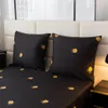 A close-up view of a bed with black bedding featuring a golden floral pattern. Produktbild-Vorschau