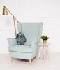 A plush bunny sits on a light blue armchair next to a small side table with a plant and a floor lamp. Anteprima dell’immagine prodotto