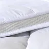 A close-up view of a white mattress topper with a textured mesh layer. Produktbild-Vorschau