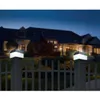 Two solar-powered fence post lights illuminate a fence in front of a large house at dusk. Voir les images du produit