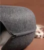 A close-up of a dark gray tunnel-shaped cat bed with a zipper. A white cat is partially visible inside the bed, with its face blurred in the background. Produktbild-Vorschau