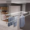 A white electric ceiling clothes dryer is shown in a room with white cabinets and shelves. Produktbild-Vorschau
