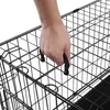 A hand is shown gripping the handle of a black wire dog crate. Produktbild-Vorschau