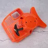 An orange chainsaw starter assembly is shown on a gray, textured surface. Náhľad obrázku produktu