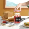 A hand is shown opening a jar of ketchup next to a loaf of bread and a slice of avocado toast. Produktbild-Vorschau