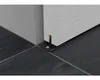 A close-up view of a sliding door hardware fitting installed on a tiled floor at the base of a wall. Náhled obrázku produktu
