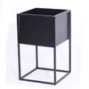 A black metal planter stand with a square pot on a white background. Produktbild-Vorschau