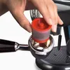 A hand is inserting a red coffee capsule into a portafilter of an espresso machine. Podgląd zdjęcia produktu