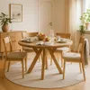 A dining room scene with a round wooden table and chairs, set for a meal. Voir les images du produit