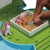 A hand is placing a small blue accessory into a miniature playset featuring two toy ponies. Produktbild-Vorschau
