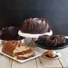 A collection of bundt cakes and mini bundt cakes arranged on cake stands on a wooden table. Podgląd zdjęcia produktu