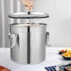 A person is lifting the lid off a large stainless steel container, with steam rising from inside. The container is on a table with some food items in the background. Produktbild-Vorschau