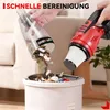 A person is emptying the dustbin of a red and black handheld vacuum cleaner into a white trash can. Podgląd zdjęcia produktu