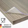A transparent or matte PVC table protector is shown on a wooden table. Produktbild-Vorschau