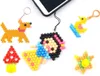 A collection of small, colorful bead crafts, including a dog, a mushroom, a duck, a star, and a character resembling Snow White, are arranged on a white background, with a portion of a smartphone visible at the top. Náhľad obrázku produktu