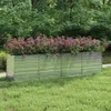 A raised garden bed filled with flowering plants sits on a lawn, with trees in the background. Produktbild-Vorschau