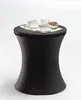 A dark brown rattan side table with a lid, holding two cups of coffee, a creamer pitcher, and a small bowl of nuts. Podgląd zdjęcia produktu