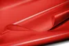 A close-up, abstract view of a red PVC tarp material, folded and curved to show its texture and sheen. Voir les images du produit