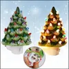 Two ceramic Christmas tree night lights, one green and one brown, are displayed against a snowy background. A close-up inset shows how the plug prongs can be rotated. Náhľad obrázku produktu