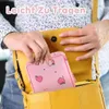 Rosa Tasche mit Pfirsichmuster, die von einer Person in eine gelbe Handtasche gelegt wird Náhľad obrázku produktu