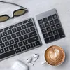 A flat lay of a Satechi numeric keypad, keyboard, sunglasses, wireless earbuds, and a cup of coffee with latte art. Voir les images du produit