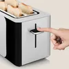 A close-up shot of a person's finger pressing the lever of a toaster, with slices of bread visible inside. Voir les images du produit