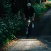 A person riding a bicycle on a path at dusk, illuminated by the bike's headlight. Produktbild-Vorschau