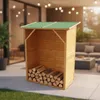 A wooden firewood storage shed with a green roof, filled with logs, is placed on a patio next to a grassy area. In the background, there is an outdoor living space with furniture and string lights. Produktbild-Vorschau