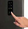 A hand is pressing a button on the control panel of a black appliance. Náhľad obrázku produktu