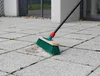 A broom is shown cleaning a patch of dirt on a paved patio. Anteprima dell’immagine prodotto