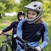 Two children wearing mountain biking gear and helmets are on their bikes outdoors. Podgląd zdjęcia produktu