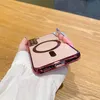 A hand holding a pink phone case with a magnetic ring on a wooden table. Anteprima dell’immagine prodotto
