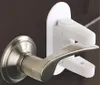 A close-up view of a white child safety lock attached to a silver door handle. Náhled obrázku produktu