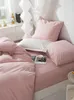 A neatly made bed with pink satin bedding and pillows, a book and a teacup on the bed. Podgląd zdjęcia produktu
