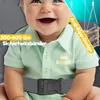 A close-up of a smiling baby wearing a light green polo shirt and a gray safety harness, with marketing text overlays. Produktbild-Vorschau
