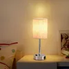 A bedside table with a lamp and a pillow. Produktbild-Vorschau