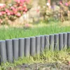 A row of dark gray garden edging posts in the grass, with pink flowers blurred in the background. Produktbild-Vorschau
