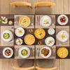A top-down view of a dining table set for a meal, featuring multiple place settings with plates of food, cutlery, and drinks. Voir les images du produit