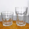 Two clear glasses of different sizes are placed on a wooden surface against a white background. Náhled obrázku produktu