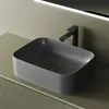 A dark gray ceramic basin with a black faucet is placed on a light green countertop. Produktbild-Vorschau