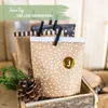 A close-up of an advent calendar with numbered bags, decorated with pine cones and fir branches, set against a wooden background. Náhľad obrázku produktu