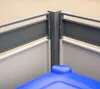 Close-up view of a corner of a grey metal trash can enclosure with a blue lid visible in the foreground. Náhled obrázku produktu