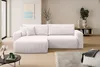 A modern living room with a white sectional sofa, a coffee table with decorative items, and a wooden shelf with books and plants.