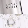 A close-up view of a modern chandelier, showing the metallic top part with ventilation slots and hanging crystal elements. Produktbild-Vorschau