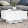 A white coffee table with a cup and a plant on it, placed in front of a gray sofa. Produktbild-Vorschau